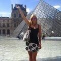 A woman in black and white dress standing next to pyramid.